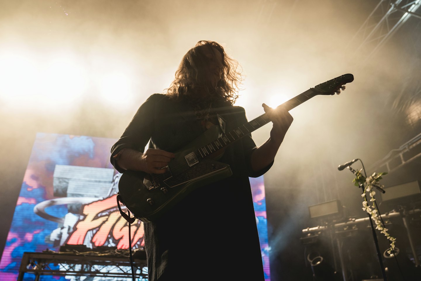 Musiker spelar elgitarr på en rökig konsertscen.