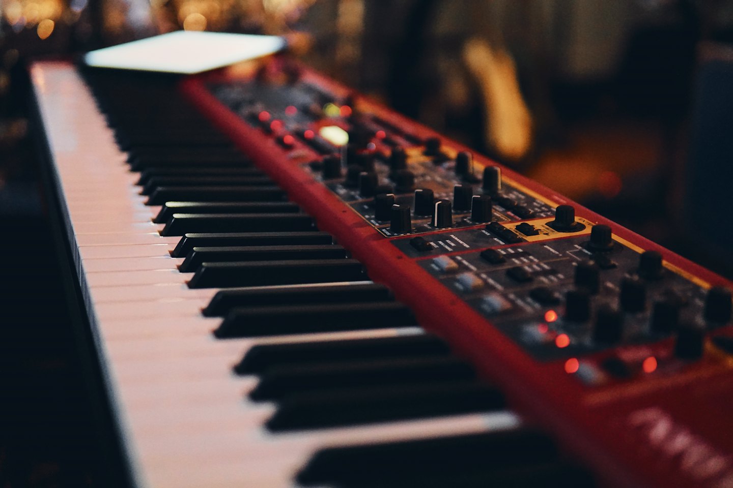 Rött synthesizerklaviatur med belysta kontroller och tangenter.